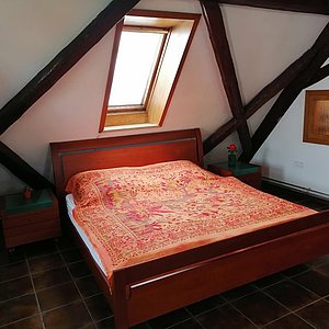Schlafzimmer mit Doppelbett unter Daschräge mit Fachwerkbalken und Dachfenster